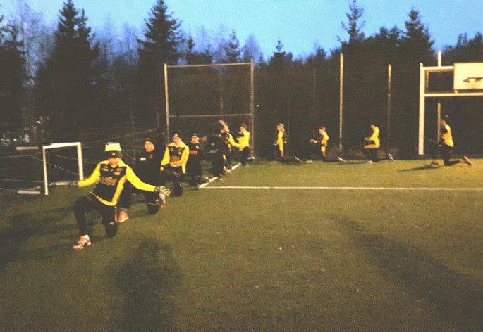Fotbollsspelare gör sps-övningar i grupp på fotbollsplan
